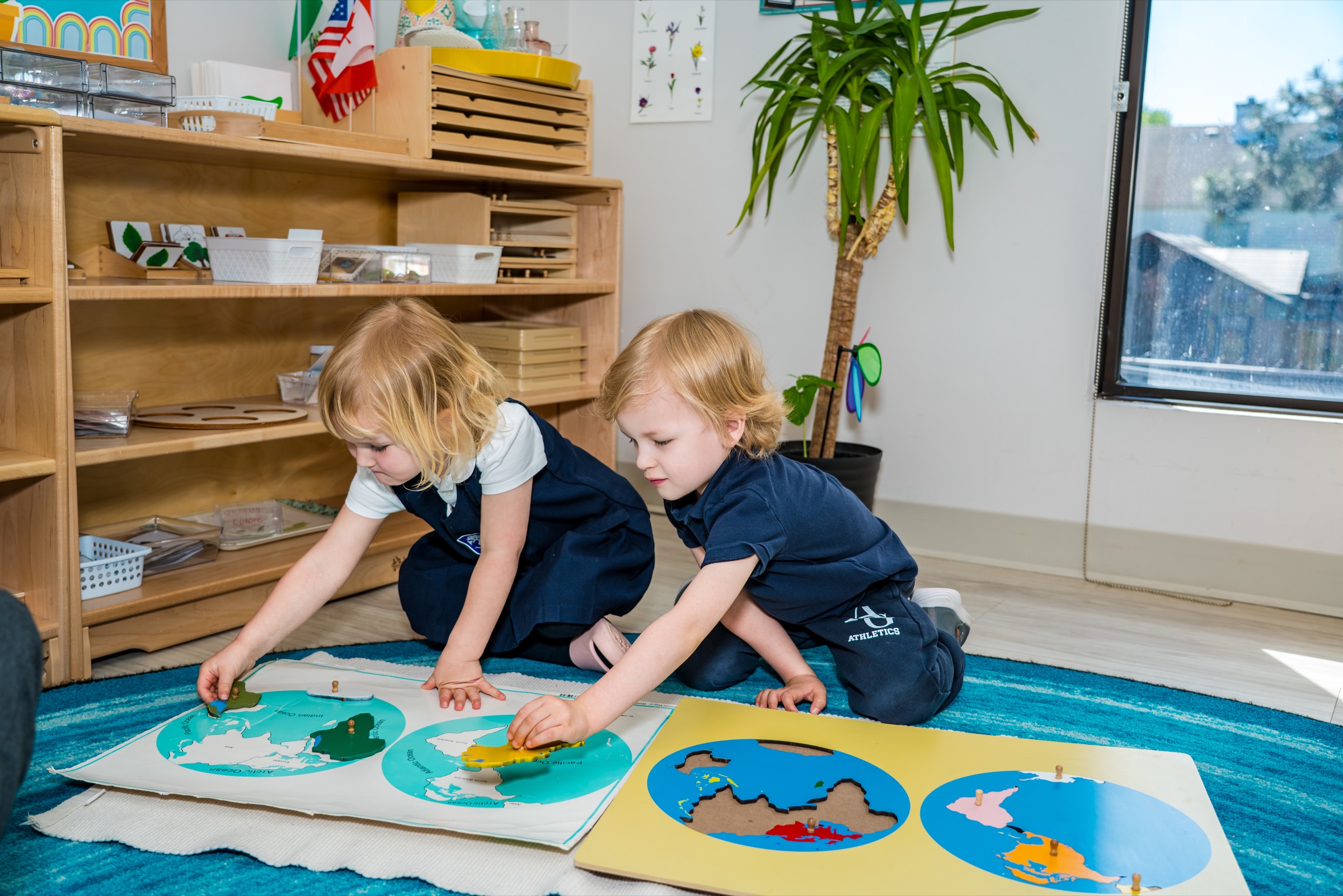 Two Casa students working on a Montessori world map puzzle